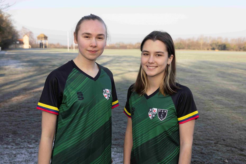two playersof the girton and murray edwards women's football team standing on the sports pitches